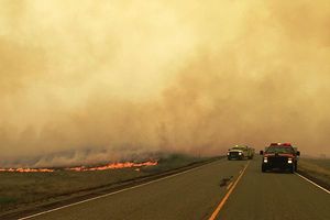 Prairie fire next to road with firetrucks