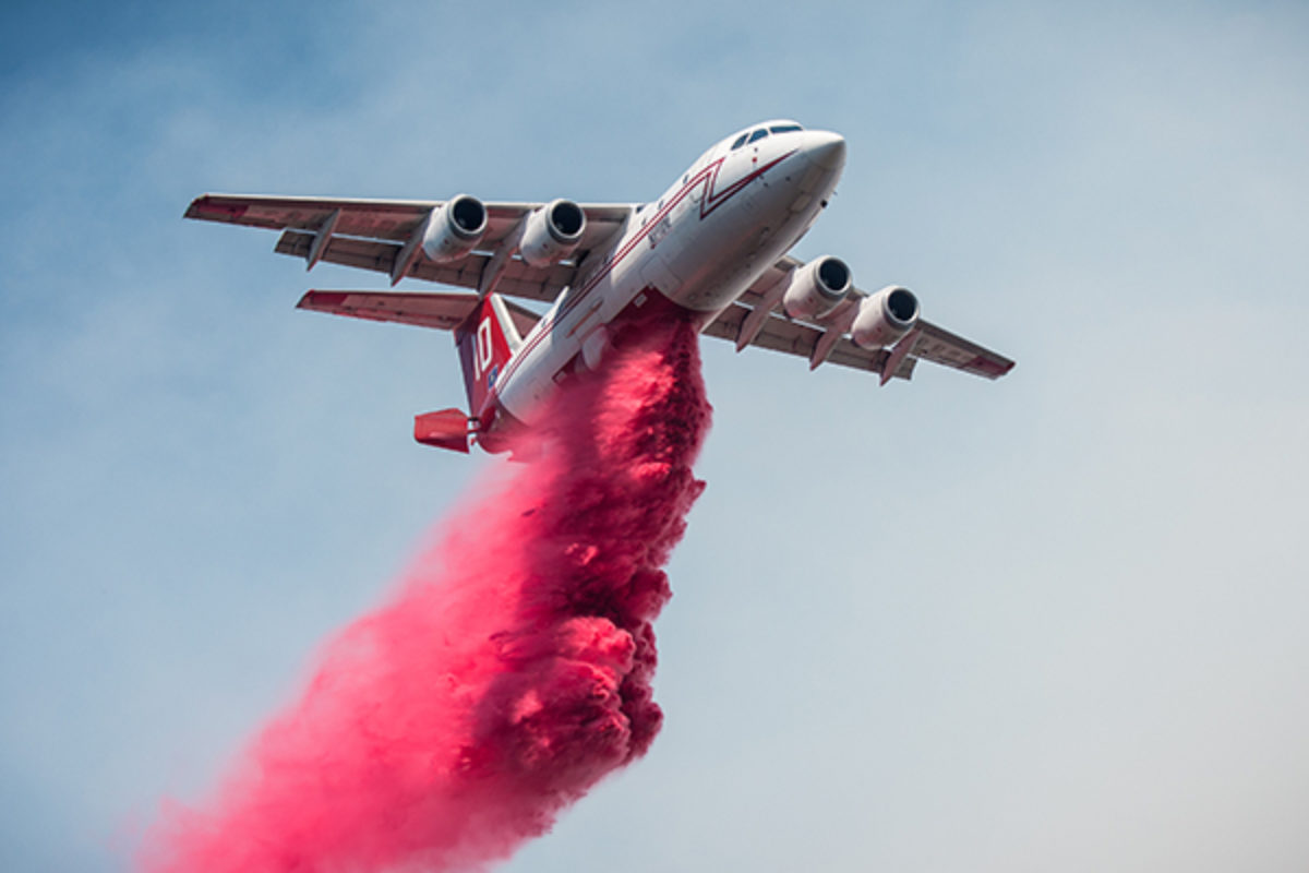 Airplane dropping fire suppressant over wildfire