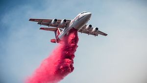 Airplane dropping fire suppressant over wildfire