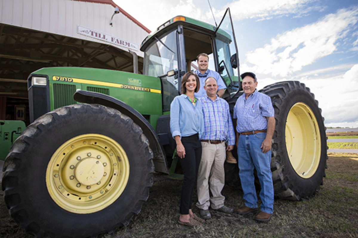Multi-generational family standing in front of their John Deere tractor