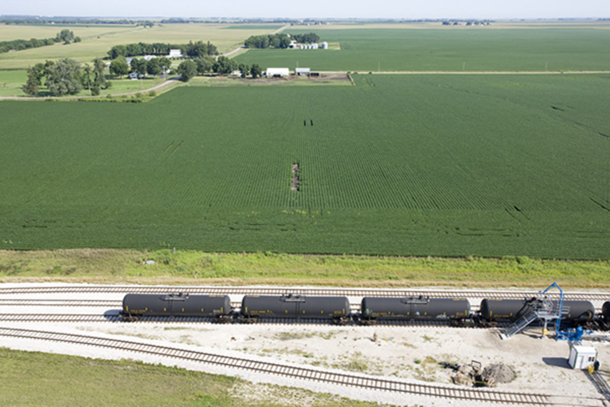 Train carrying Ethanol driving past corn field
