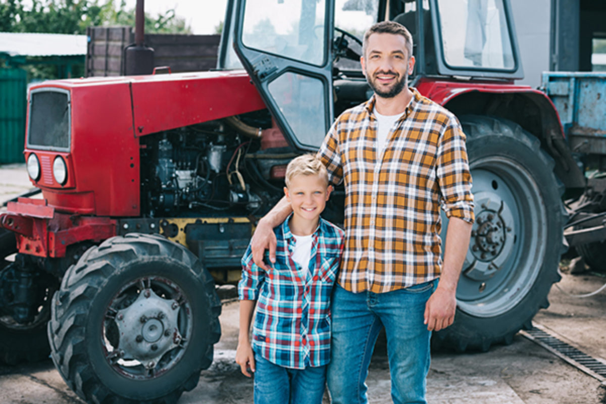 Farmer and son standing in front of red tractor