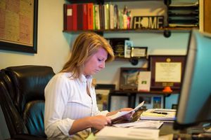 Woman in home office reviewing paperwork